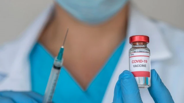 Profissionalreal ao vivojaleco segura seringa e frascoreal ao vivovidro escrito 'Covid-19 vaccine'