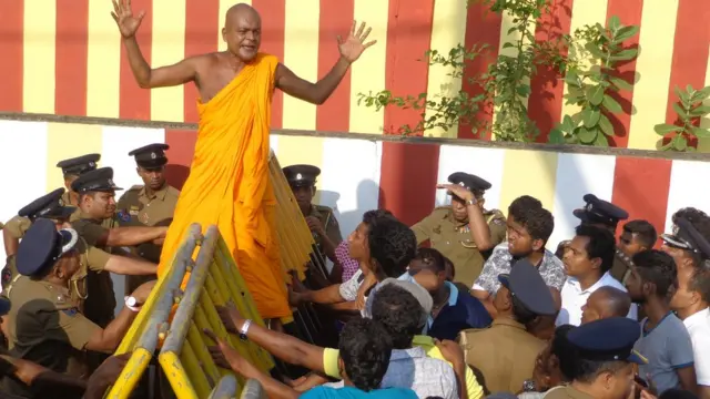 வீதி தடையை கடக்க முற்படும் பௌத்த பிக்கு