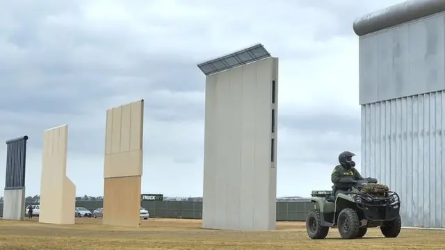 Picha ya maktaba ya afisa wa udhibiti wa mpaka akiendesha pikipiki kwenyekupitia kwenye mradi wa awali wa ujenzi wa ukuta wa mpaka uliopendekezwa na rais Trump Donald San Diego, California. Novemba 1, 2017