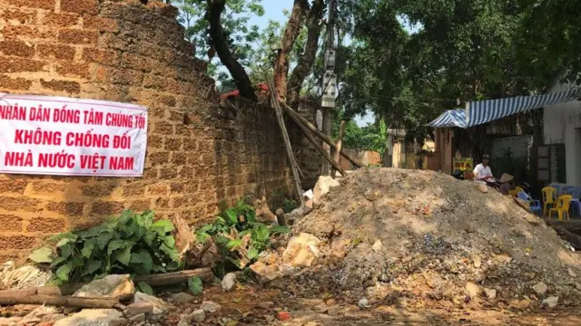 Người dân xã Đồng Tâm ở Mỹ Đức treo khẩu hiệu cạnh đường vào làng bị đổ đất lập ụ ngăn cản giao thông