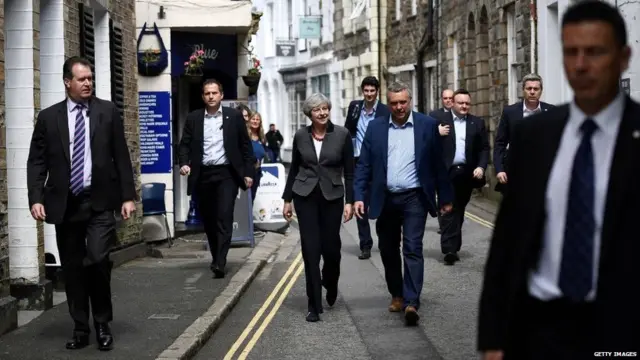 Britain's Prime Minister Theresa May (C) is flanked by security guards as she walks in Mevagissey, south-west England, during the 2017 election campaign