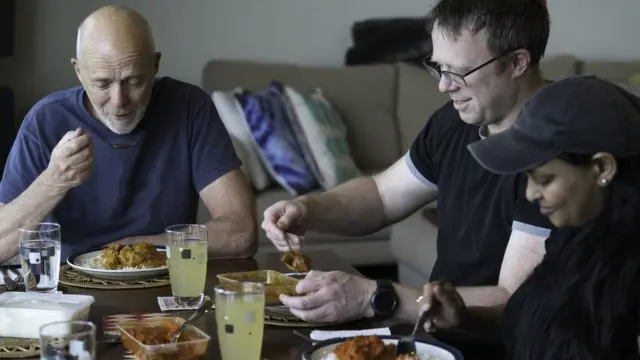 Três pessoas comendo na mesa