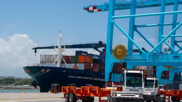 Una grua traslada contenedores en el puerto.