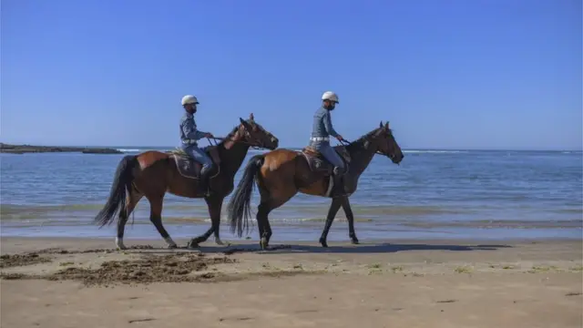 Deux officiers en uniforme montent à cheval le long du rivage.