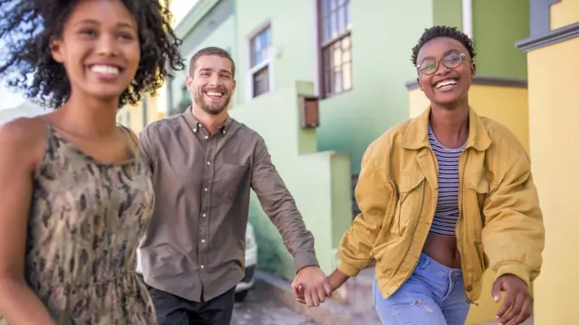 Grupo de tres amigos riendo en la calle.