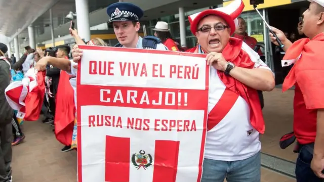 Un peruano con un letrero de "¡Que viva el Perú, carajo!"