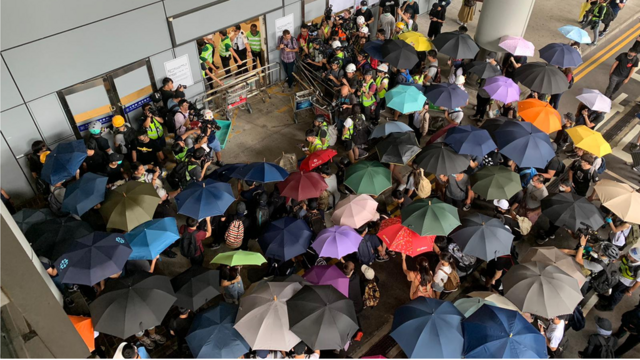 示威者用雨伞形成伞阵，试图堵塞香港国际机场地面抵达大厅的其中一个出入口。