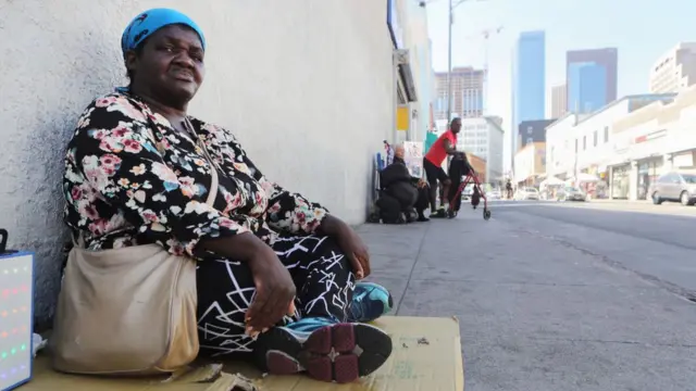 Homeless woman sitting on cardboard in a Los Angeles street
