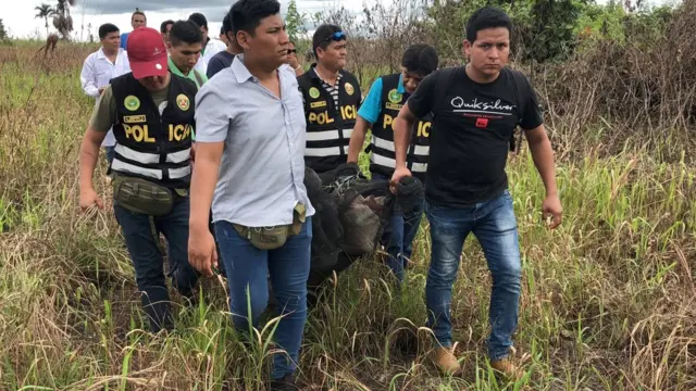 Agentes de la policía cargan el cuerpo del canadiense fallecido en la Amazonia peruana, Sebastian Woodroffe.