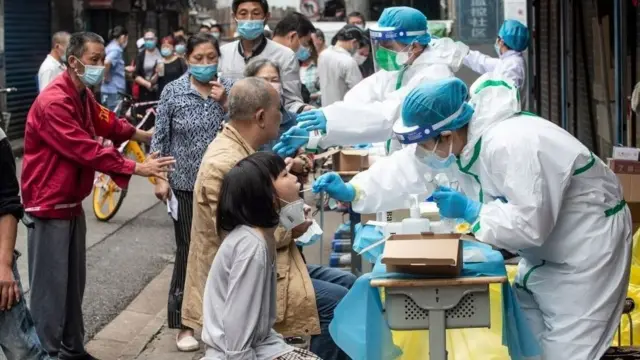 Medical workers take swab samples from residents to be tested for the COVID-19 coronavirus, in a street in Wuhan in China's central Hubei province on May 15, 2020.