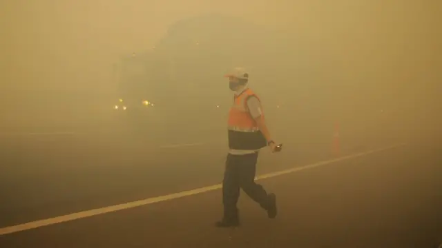 Petugas jalan tol Indralaya-Palembang melakukan pengaturan lalu lintas saat terjadi kabut asap akibat kebakaran lahan gambut di Desa Pulau Semembu, Indralaya Utara, Ogan Ilir, Sumatra Selatan, Senin (05/08/2019).