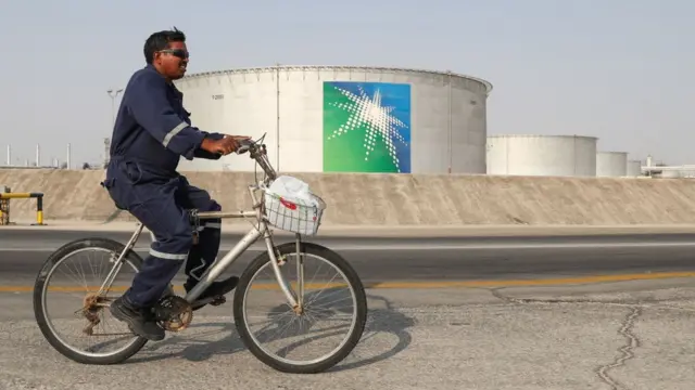 Um homem conduz uma bicicleta nas instalações da petrolífera Aramco