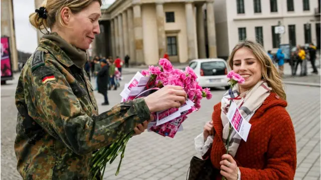 Một người lính của Bundeswehr trao hoa cho một phụ nữ qua đường vào Ngày Quốc tế Phụ nữ 8 tháng 3 năm 2019 ở Berlin, Đức