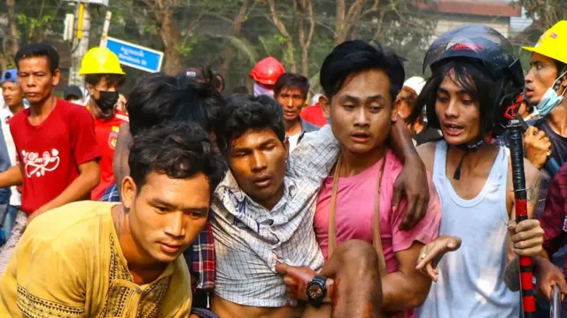 A resident, who was injured during a crackdown by security forces on demonstrations by protesters against the military coup, is carried to safety in Yangon's Hlaing Tharyar township, 14 March 2021