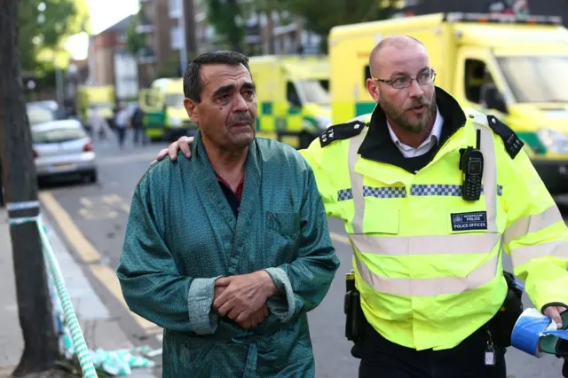 Un inquilino de la Torre Grenfell junto a un policía de Londres.