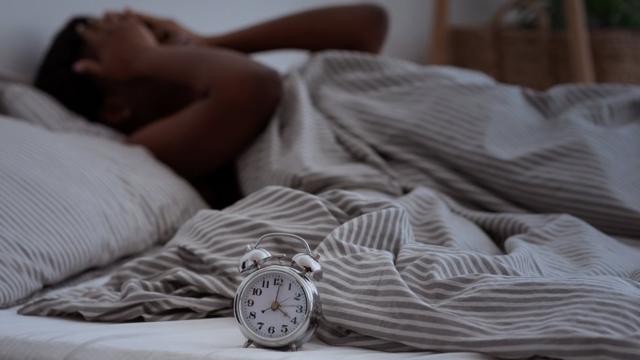 Mulher deitada na cama com a mão na cabeça