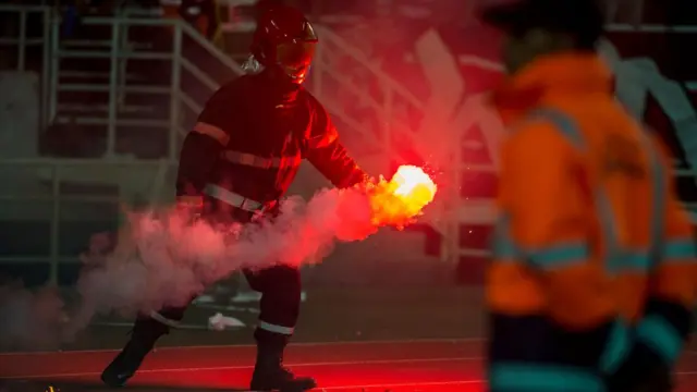 Өрт өчүрүү кызматы стадионго ыргытылган фаерлерди өчүрүүдө (өткөн жылдын сентябрындагы Марокко - ТАР беттеши).