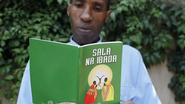 Un homme lisant un livre religieux écrit en swahili.
