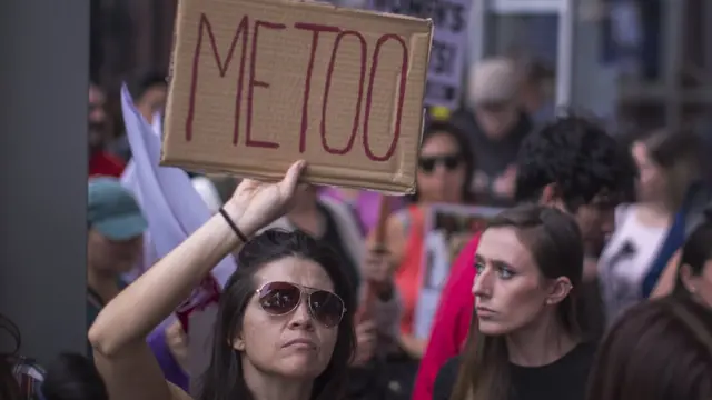 Una mujer sostiene una pancarta con el mensaje "Me Too" en apoyo a las mujeres que han denunciado acosos y abusos sexuales en el último mes.