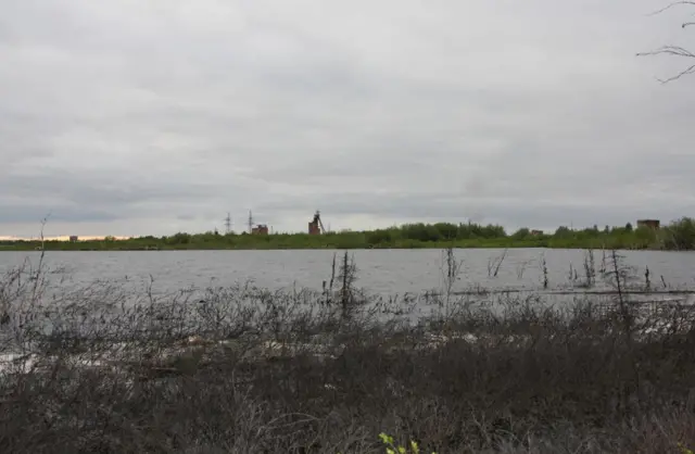 Водоем на месте кладбища заключенных ОЛП №1 Инталага / ЛО №1 Минлага. На заднем плане: строения первых интинских шахт. Республика Коми, г.Инта, пос. Первый Горный. Фото 22.06.2009