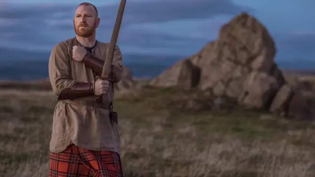 Мужчина в килте с меяом в руках