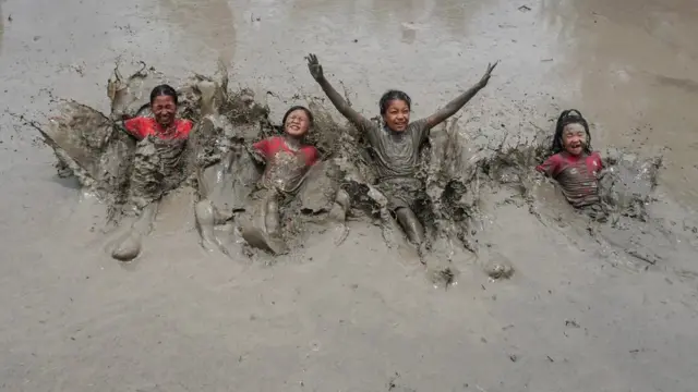 भात लावणीच्या हंगामाच्या सुरुवातीचं प्रतिक असलेल्या नेपाळच्या राष्ट्रीय धान दिनानिमित्त चिखलात खेळण्याचा आनंद लुटणारी चिमुकली मुले.