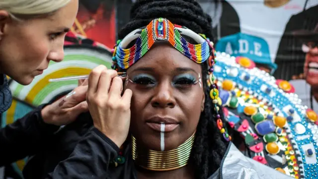 عارضة تتزين بوضع الألوان والمساحيق استعداد للمشاركة في عروض المهرجان.