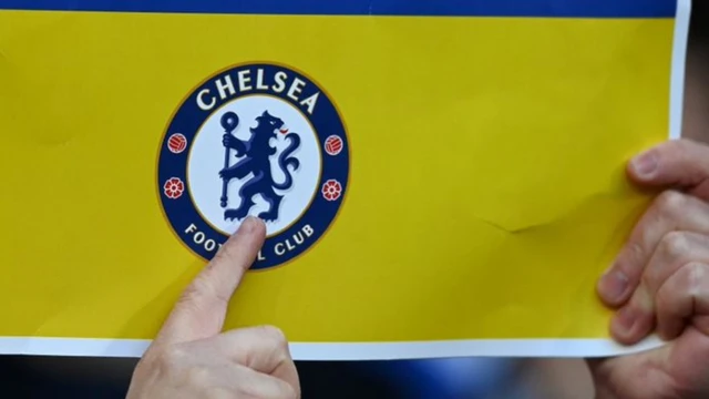 A Chelsea fan showing a placard with the Ukrainian flag and the club crest