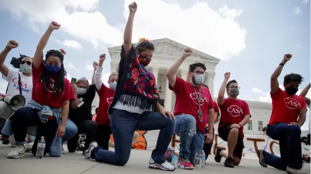Grupo de hombres y mujeres arrodillados con el puño en alto ante la sede de la Corte Suprema de EE.UU.