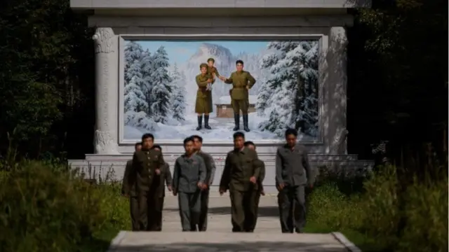 2019년 9월 12일 삼지연 인근 김정일 국방위원장의 생가라 일컬어지는 비밀캠프 입구에서 아들 김정일을 부인 김정숙과 안고 있는 고(故) 김일성 주석의 모습을 그린 벽화 앞을 북한 주민들이 걷고 있다