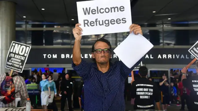 Мужчина с плакатом "Добро пожаловать, беженцы"