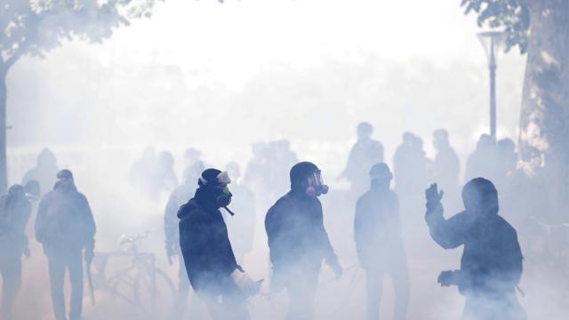 Protesters wear protective masks against tear gas in clashes with French police forces during a demonstration of workers