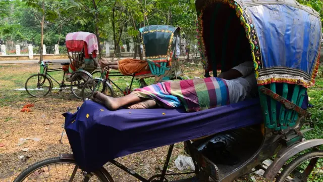 প্রচণ্ড গরমে কাজ বন্ধ রেখে বিশ্রাম নিচ্ছেন একজন রিক্সাচালক