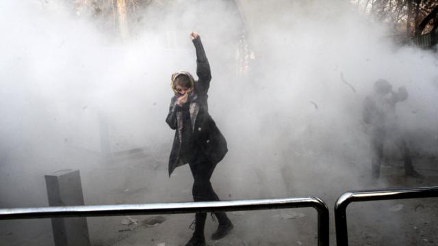 テヘラン大学の抗議集会で警察と衝突し、こぶしをかかげる女子学生