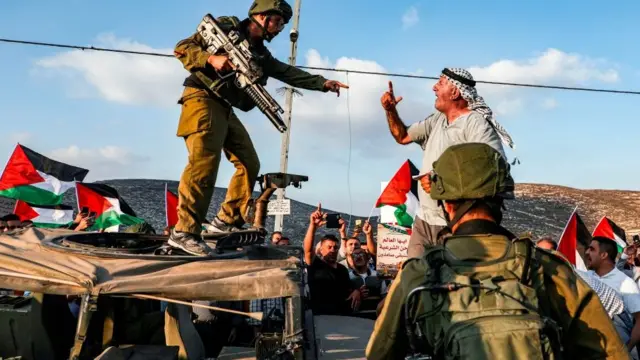 Homem brigam, um deles fortemente armado,como apostar no blaze futebolmeio a bandeiras da Palestina e outros