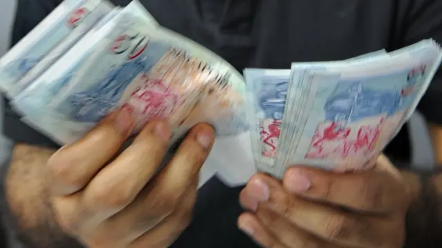 સિંગાપોરની કરન્સી ગણતો એક વ્યક્તિ