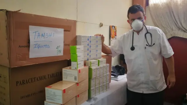 Padre Portillo com caixas de remédios e equipamentos