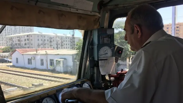 Вид из кабины водителя поезда. Перед ним рельсы и дома.