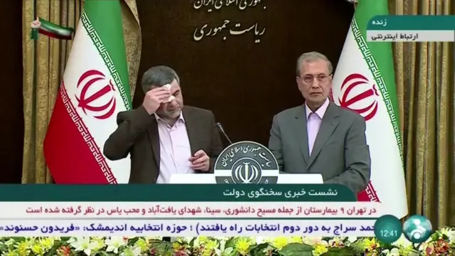 Iranian Deputy Health Minister Iraj Harirchi (L) mops his brow during a news conference on 24 February 2020