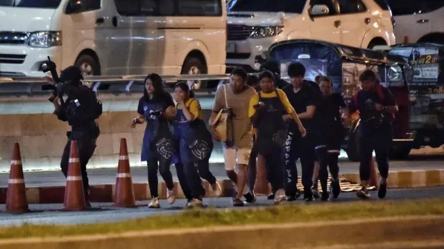 被挟持的民众在军警护送下离开枪击现场。