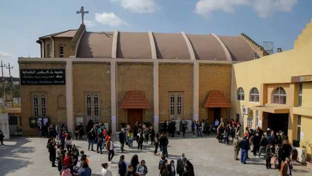 بغداد – أسر مسيحية تتجمع أمام كنيسية مار كوركيس للكلدان في بغداد بانتظار وصول البابا