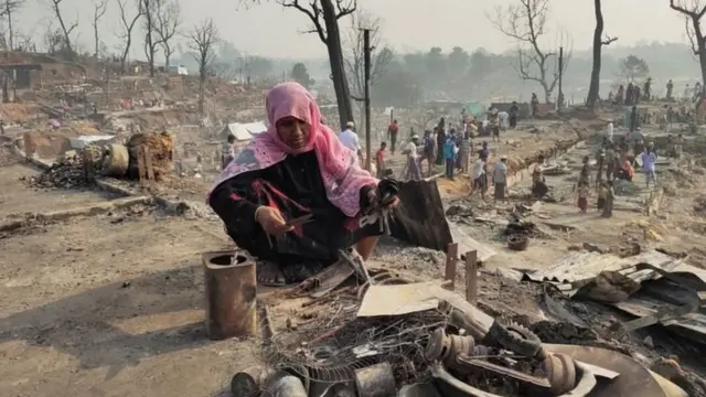 অগ্নিকাণ্ডের ধ্বংসস্তুপ থেকে অক্ষত গার্হস্থ্য উপকরণ খুঁজে ফিরছেন এক রোহিঙ্গা নারী।
