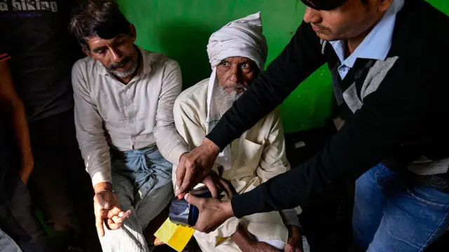 बैंक के एक अधिकारी ग्रामीण की मदद करते हुए