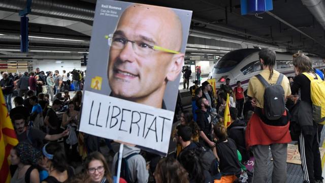 Protesters hold a picture of deposed Catalan regional government"s foreign relations chief Raul Romeva reading "Freedom" as they block train tracks at the Sants Station in Barcelona during a strike called by a pro-independence union in Catalonia on November 8, 2017.