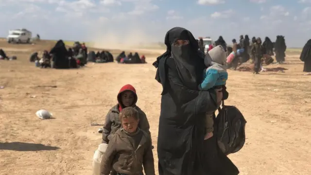 امرأة تحمل طفلا وتصحب أطفالا أكبرسنا