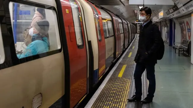 Londra'da metroya binmek üzere olan maskeli bir erkek