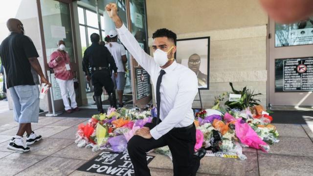 أحد مشيعي فلويد وهو راكع على صورة أمام الزهور في كنيسة "فونتين أوف برايز" في 8 يونيو/حزيران 2020 في هيوستن، تكساس