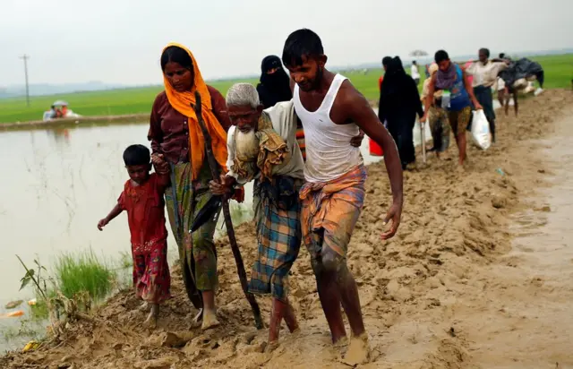 people helping an old man through mud