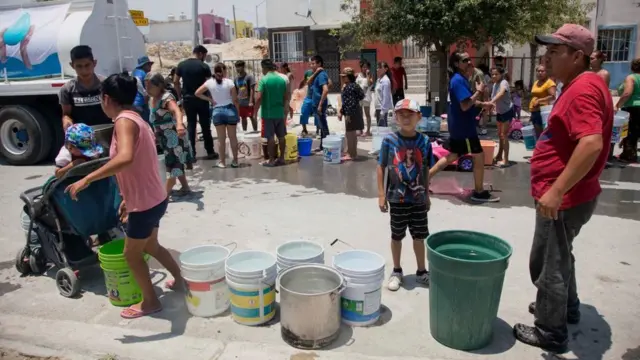 Pessoas fazem fila com baldes para receber água