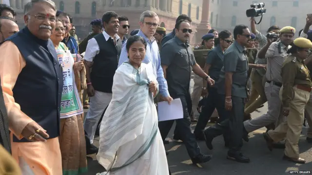 Mamata Banerjee (C) walks with former chief minister of Jammu and Kashmir Omar Abdullah and other politician towards the President's House in protest against the removal of high denomination currency notes from circulation in New Delhi on November 16, 2016.